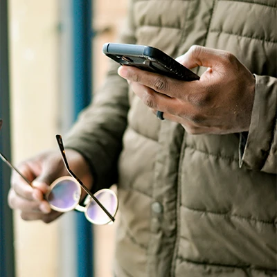 Man in puffer jacket looks at his phone while holding his jacket