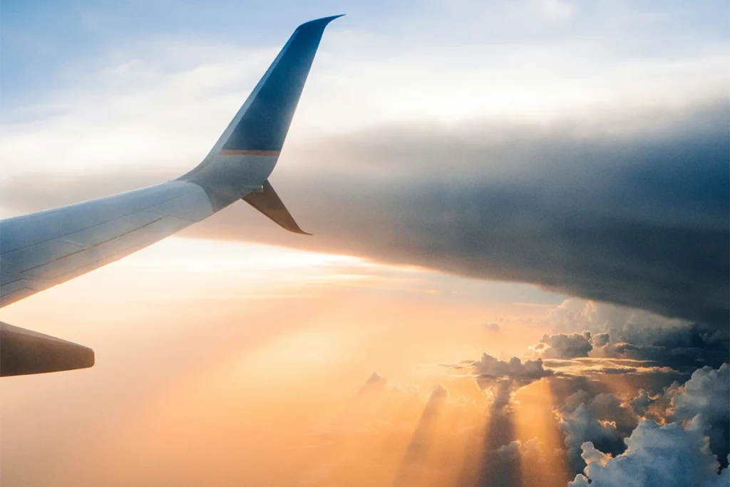 View through the clouds over the wing of a commercial airliner as a person emigrates