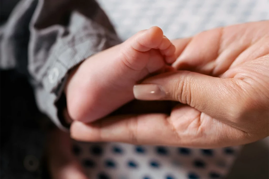 hands hold an infants foot tenderly