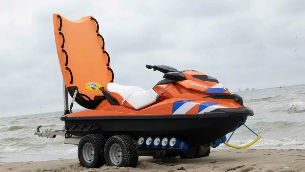 Orange jetski on the beach with a tow sled, mounted on a trailer